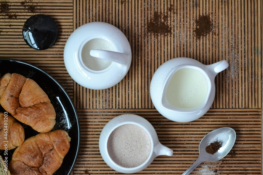 Coffee set with coffee and milk next to a plate of chocolate croissants Coffee set with coffee and milk next to a plate of chocolate croissants