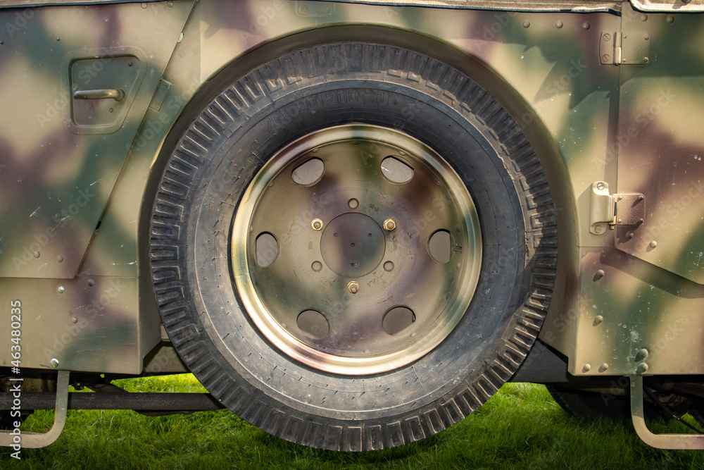 A spare wheel attached to the body of an retro .army vehicle A spare wheel attached to the body of an retro .army vehicle