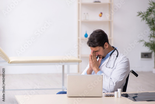 Young male doctor in wheel-chair working in the clinic