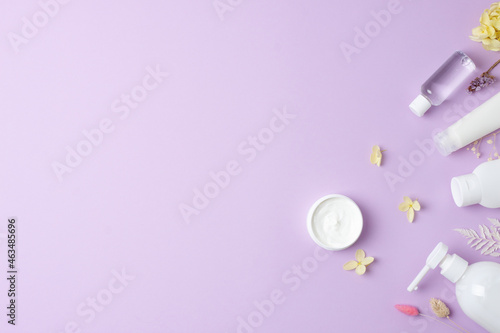 Cosmetic skin care products with flowers on rose background. Flat lay, copy space