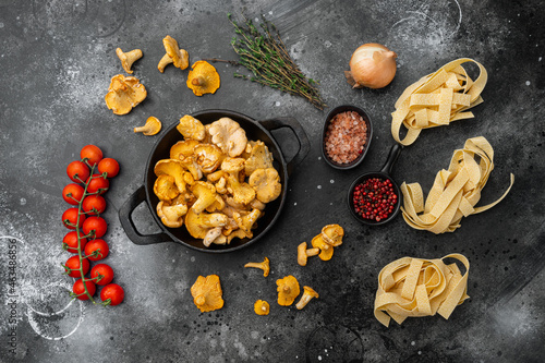 Ingredients for making italian pasta with mushrooms chanterelles, on black rustic table background, top view flat lay