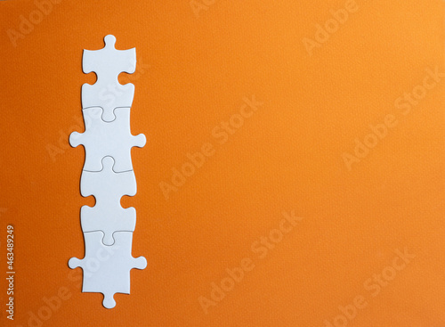 4 white jigsaw tiles joined together. horizontal image with orange background. copy space. space on the tiles to place letters or numbers.