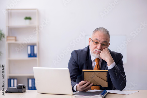 Old male employee missing his wife at workplace