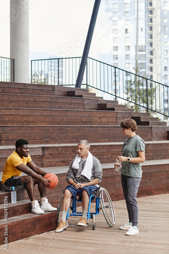 Man with disability discussing basketball game together with the athlete on the stadium outdoors