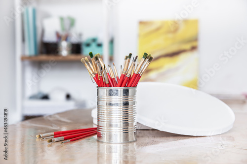 A metal can with a set of brushes for painting in an art workshop.