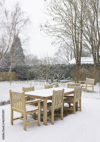 Snow falling on garden patio furniture in winter, UK