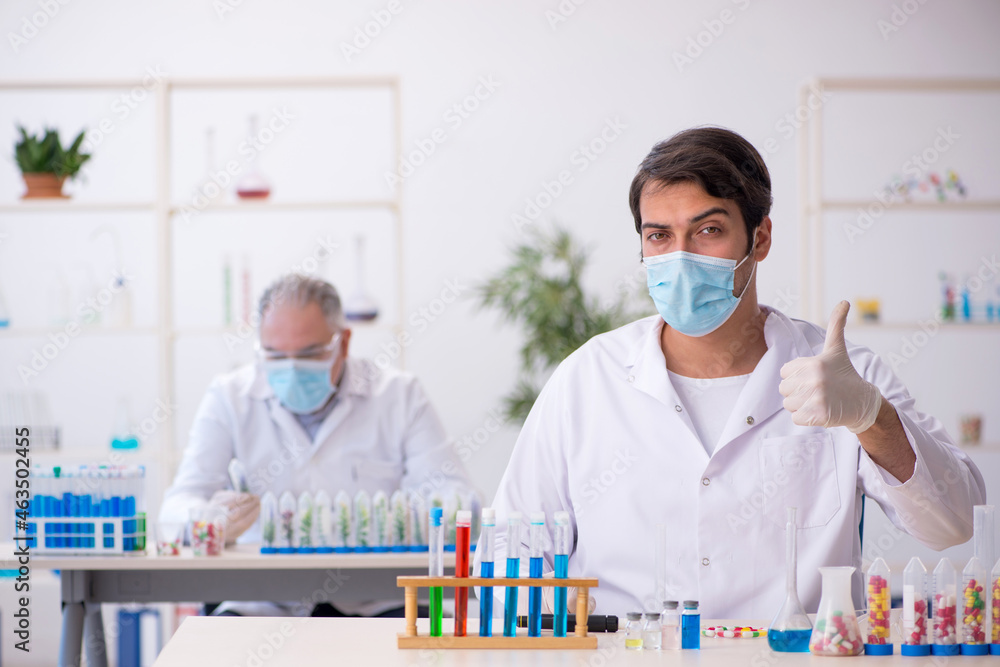Two male chemists in drugs synthesis concept at the lab Two male chemists in drugs synthesis concept at the lab