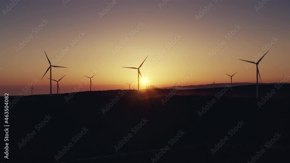 Wind turbines farm produce energy in sunset nature landscape. Power electric station, renewable green environment concept. Modern windmills rotate, electricity production from planet natural resources Wind turbines farm produce energy in sunset nature landscape. Power electric station, renewable green environment concept. Modern windmills rotate, electricity production from planet natural resources