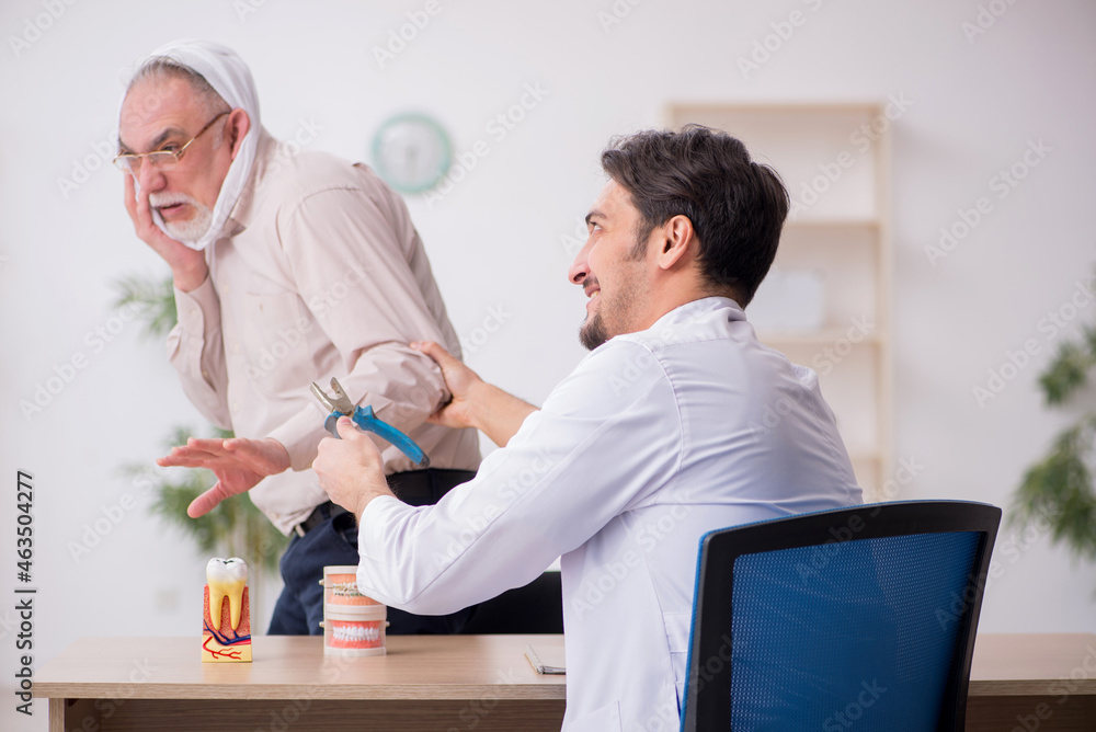 Obraz premium Old male patient visiting young male doctor dentist