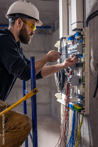 Obraz na plátně A male electrician works in a switchboard with an electrical connecting cable