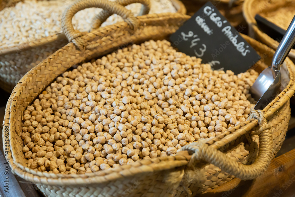 Obraz premium Dried yellowish garbanzos in wicker basket on market counter. Organic bulk foods