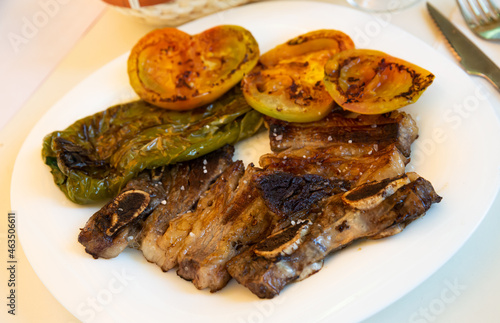 Traditional Galician Churrasco - grilled beef short ribs served with broiled tomatoes and sweet pepper