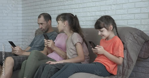 Parents using smartphones at home. A family using smartphones by their little girl on the sofa. A concept of family with digital addiction ignore each outher. photo