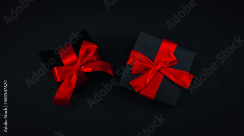 Two black small gift boxes with a red ribbon tied in a bow