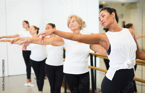 Dancing women engaged in a group class perform an exercise near the ballet barre, standing in the 2nd position of the ballet ..stance