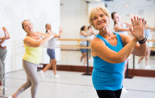 Portrait of an active mature European woman enjoying modern energetic dancing in a female group in the studio