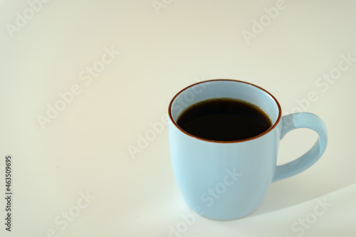 Hot black coffee in the blue coffee mug on the table.
