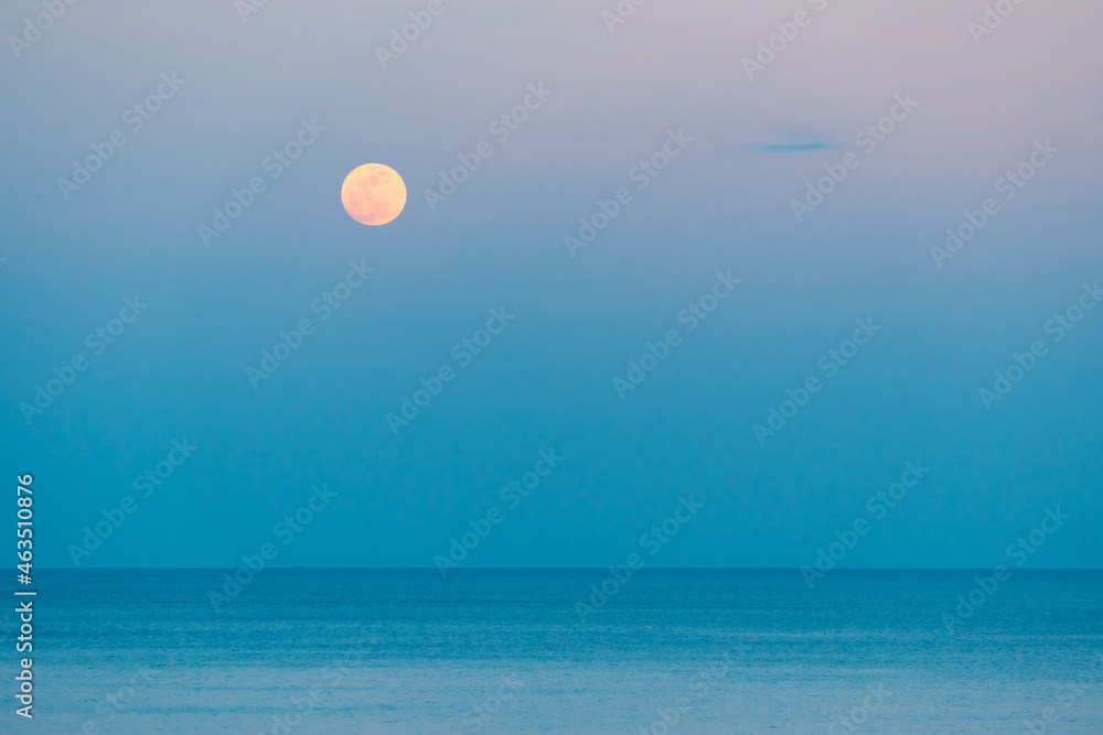Full moon over the sea against the background of the colorful sky