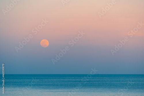 Fototapeta Naklejka Na Ścianę i Meble -  Full moon over the sea against the background of the colorful sky