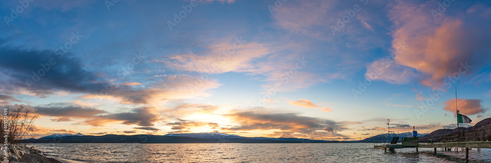 Yukon, Canada - 16th October 2021: Panoramic nature sunset in northern Canada taken during fall, autumn over a stunning lake with blue sky and dock. 
