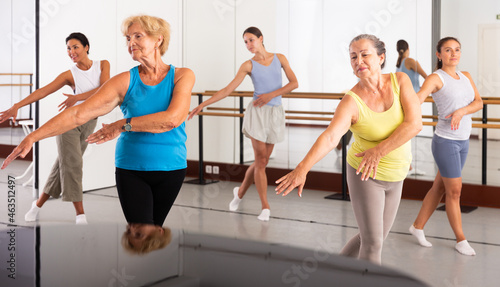 Group of various aged women dancing modern dance in studio.