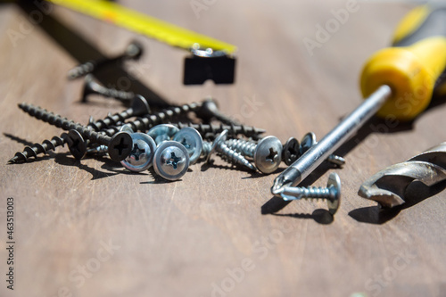 screw and screwdriver. Screwdriver and screws on a wooden surface. Hand screwdrivers and screws on a wooden background.