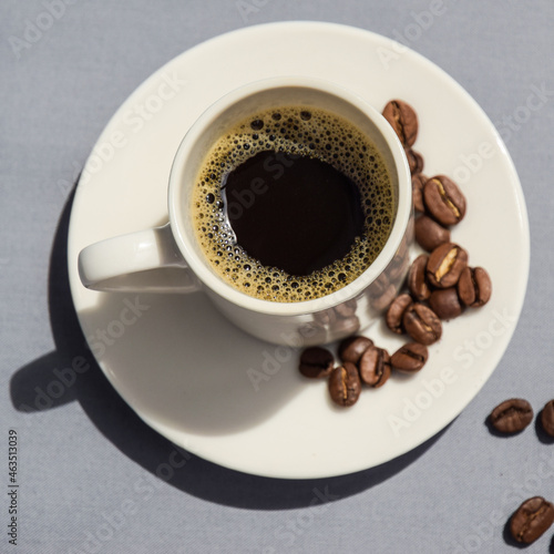 A cup of coffee in a white cup. coffee on a gray background with coffee beans top view. black aromatic coffee.