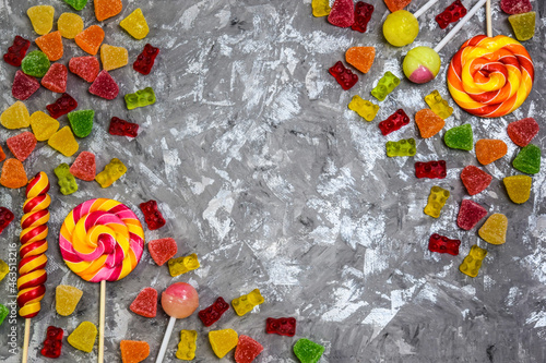 Candies of different shapes and colors on a gray wooden background. Soft focus. a place to copy. lollipops on a gray background with space to copy. Background, banner about a background with sweets.