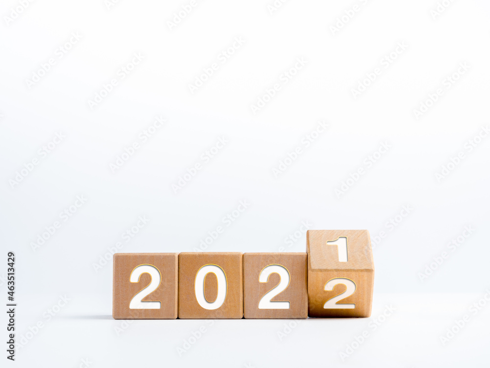 Turning year numbers for change from the calendar year 2021 changed to 2022 on wooden cube blocks isolated on white background with copy space, simple, clean, and minimal style. Turning year numbers for change from the calendar year 2021 changed to 2022 on wooden cube blocks isolated on white background with copy space, simple, clean, and minimal style.