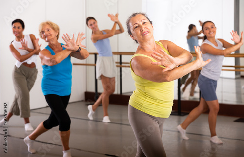 Active European woman engaged in dancing in a female group practices energetic swing in the studio