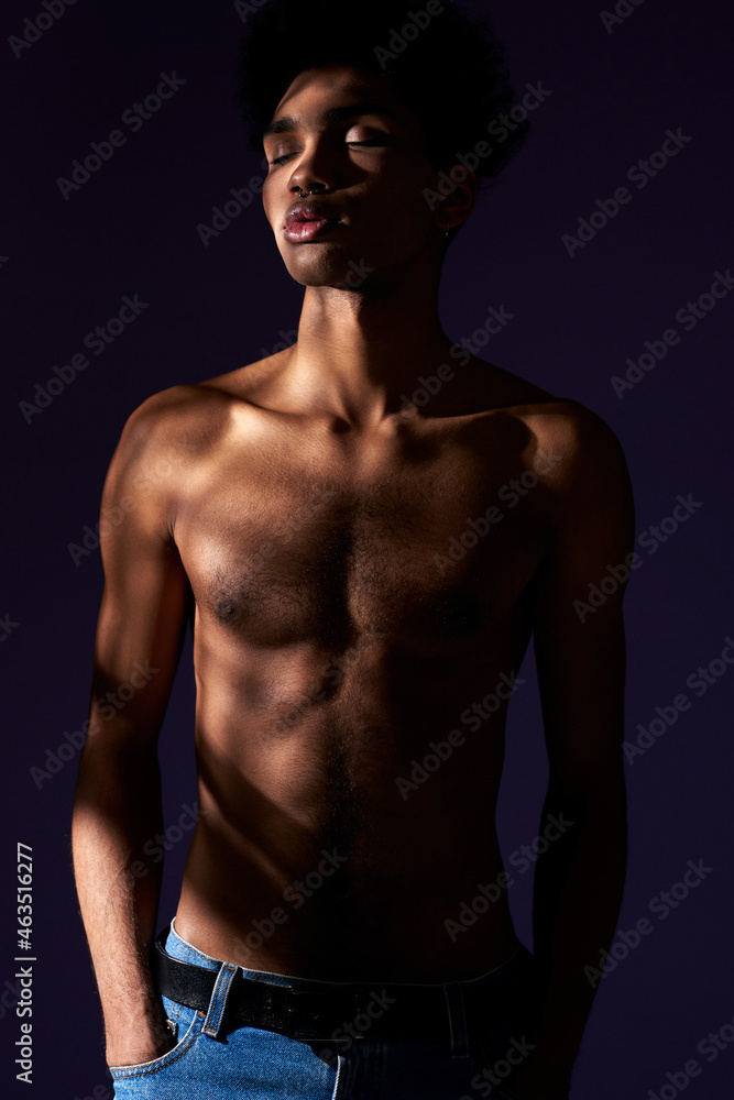 Portrait of transgender model with closed eyes stand in casual pose in shadow. Muscular trans gender