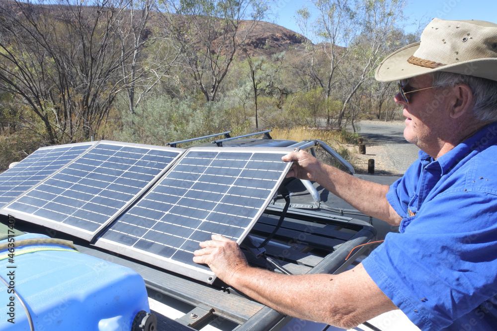 Australian man placing a portable solar panels on a car roof
