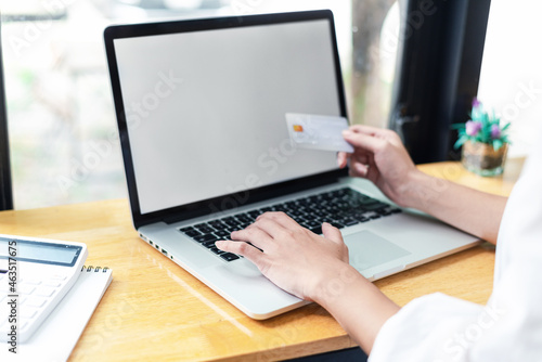 Businesswoman shopping online using laptop blank white screen holding credit card. Mock up.
