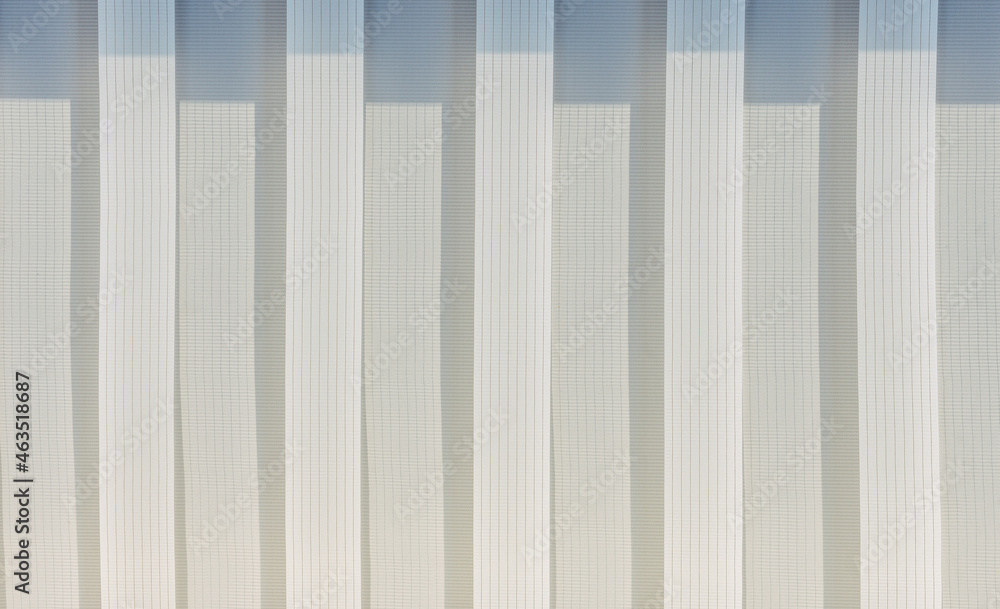 Fototapeta premium Abstract geometric vertical lines white and gray gradient color. Repeating pattern, background texture, design of striped lines. Blinds illuminated by the sun, close-up.
