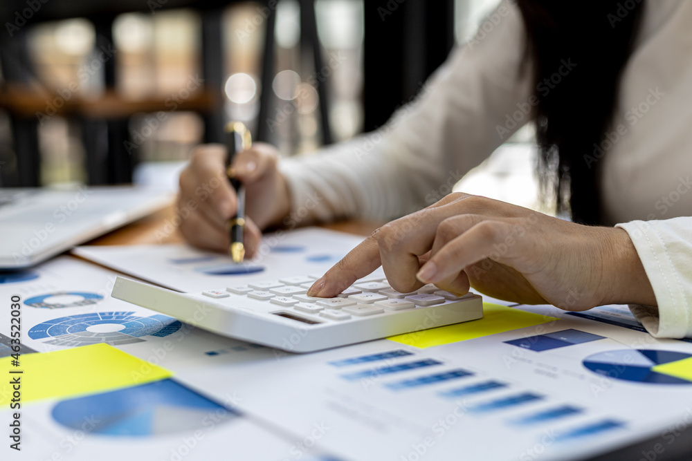 A financial worker presses a calculator to verify the accuracy of the information on the company's financial documents, she prepares the company's financial summary for a meeting with the management. A financial worker presses a calculator to verify the accuracy of the information on the company's financial documents, she prepares the company's financial summary for a meeting with the management.