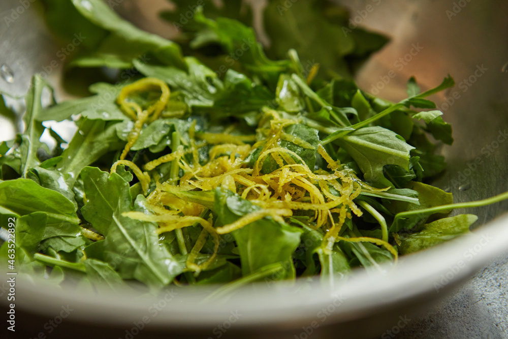 Salad with arugula and orange zest in metal bowl Salad with arugula and orange zest in metal bowl