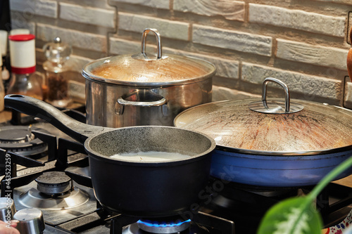 Preparing food in frying pan and casseroles on the gas stove in the kitchen