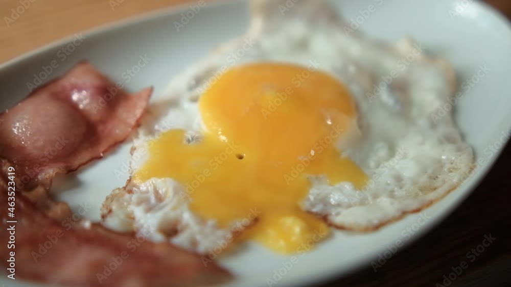 Delicious fried egg and bacon stripes with chopped herbs on white plate Delicious fried egg and bacon stripes with chopped herbs on white plate