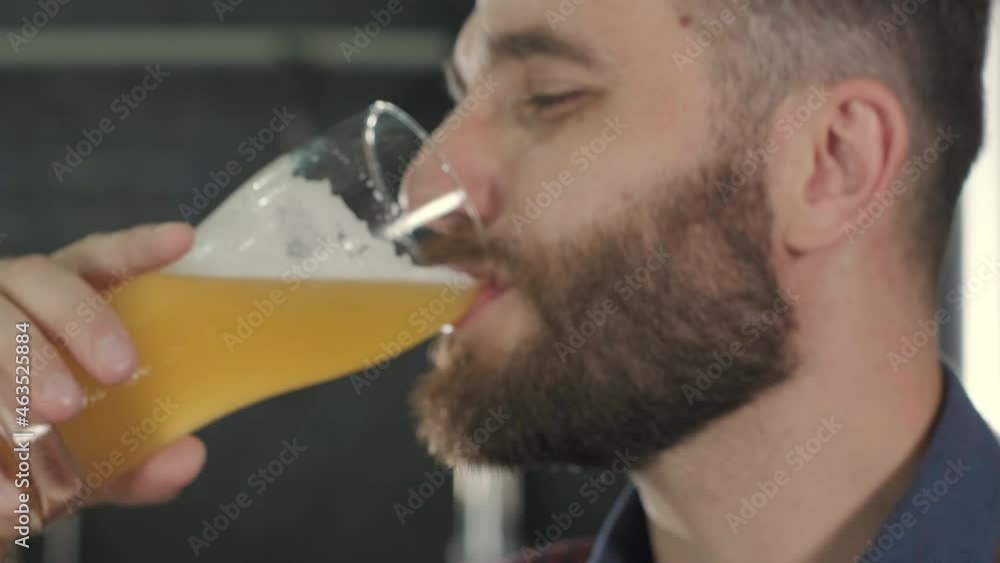 Young brewer wearing a leather apron is tasting beer at a modern brewery Young brewer wearing a leather apron is tasting beer at a modern brewery