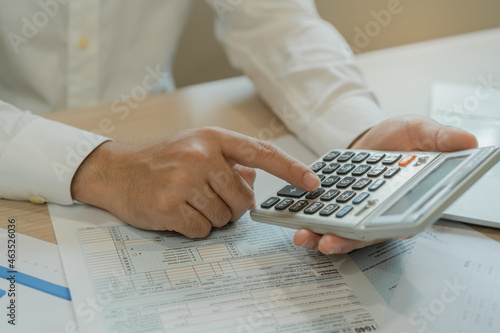 Close up hand of stress asian young businessman, male pressing a calculator to calculate tax income and expenses, bills, credit card for payment or payday at home, office.Financial, finance concept.