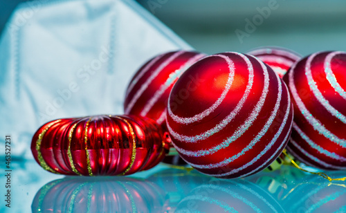 Christmas table decorated with red balls, medical white masks. Coronavirus pandemic, quarantine, 2020, 2021. New Year celebration, holiday, self-isolation, stay at home