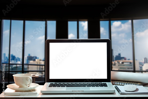 Laptop with blank screen on white desk with blurred background as concept.