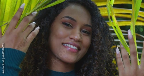 A girl drops palm branches over her face while smiling photo