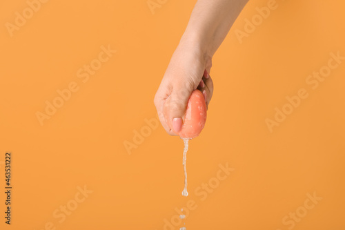 Canvas Woman squeezing wet makeup sponge on color background