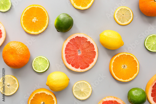Slices of different citrus fruits on grey background