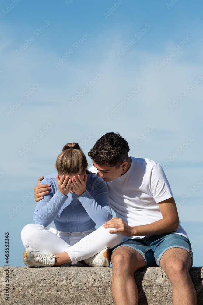 Teenage boy consoling his depressive girlfriend - obrazy, fototapety, plakaty 