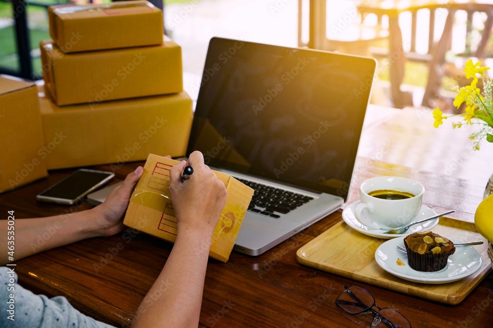 Hands of a working woman writing a list of shipping addresses for customers. Freelance business and online shopping, work at home concept. Hands of a working woman writing a list of shipping addresses for customers. Freelance business and online shopping, work at home concept.