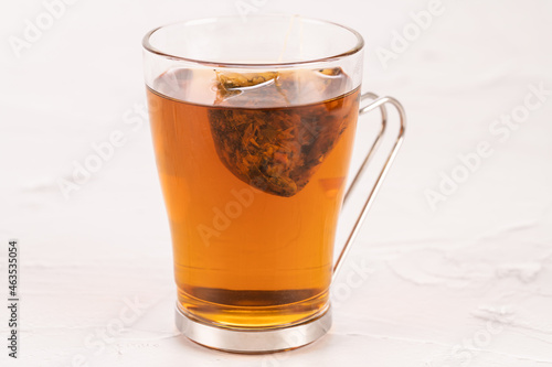 Steeping a herbal tea bag in a glass tea mug close up
