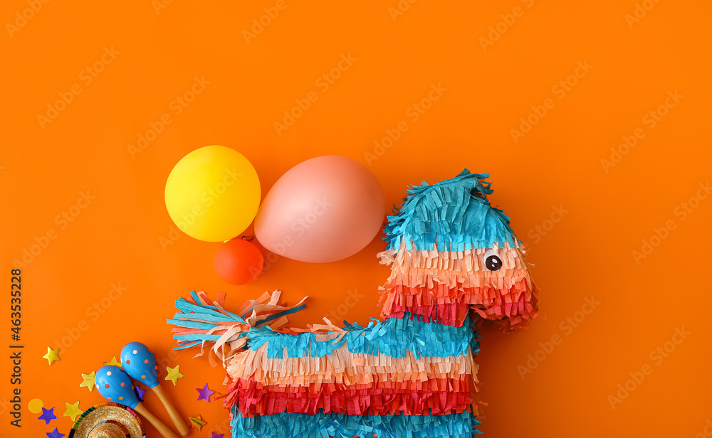 Mexican pinata with sombrero hat, balloons and maracas on color background