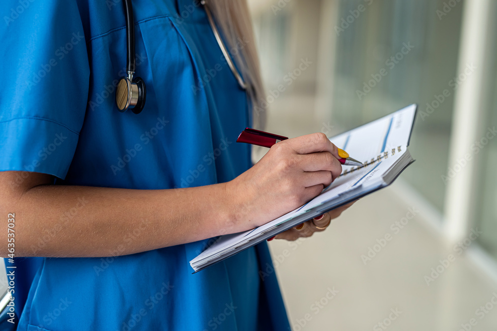 young beautiful nurse stands in the hallway in uniform, mask, gloves, stethoscope and holds a tablet young beautiful nurse stands in the hallway in uniform, mask, gloves, stethoscope and holds a tablet